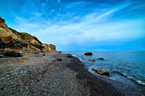 Dramatic landscape of blue sea or ocean waves rolling on rocky volcanic beach on cloudy day. Blue sky