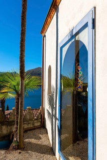 Arabic House and Patio with Palm Tree and Lake Lugano with Mountain and Sunlight in Park Scherrer in Morcote