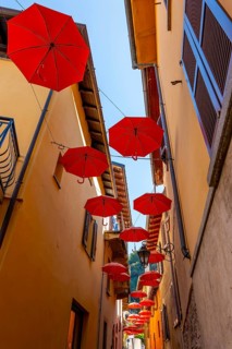 City Street in Porto Ceresio with Hanging Umbrellas in a Sunny Summer Day in Porto Ceresio