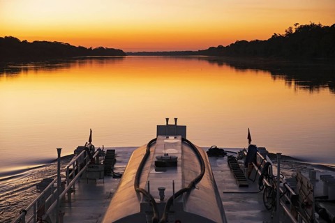 Boat sailing on the on the Mamore River at sunset in the Amazon basin