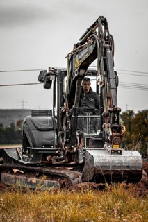 Black Yanmar mini tracked excavator during earthworks for house construction on building site