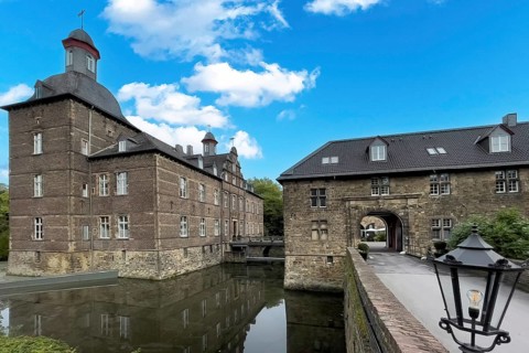 View of the main house of the moated castle Schloss Hugenpoet on the left