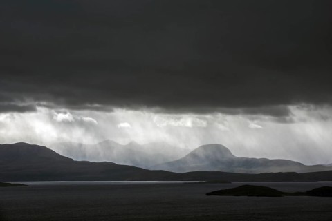 Black stormy sky and downpour during rain storm over desolate wilderness of Coigach