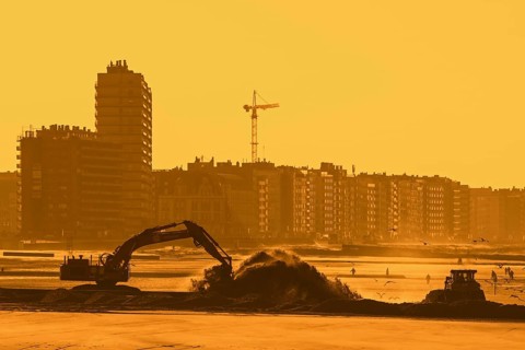 Bulldozer and hydraulic excavator installing pipeline during sand replenishment