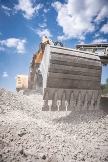 Yellow tracked excavator with large bucket for demolition recycling on construction site