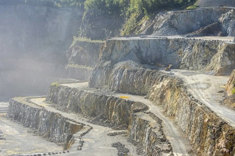 Heavy machines working in dusty porphyry quarry