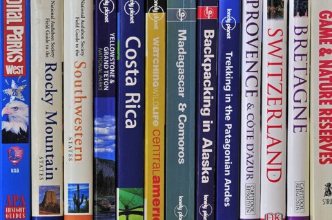 Collection of travel guides about worlwide holiday destinations on a bookshelf