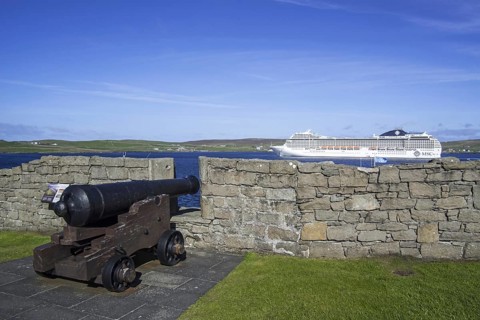 Cannon at 17th century Fort Charlotte in the centre of Lerwick and cruise ship in the Bressay Sound