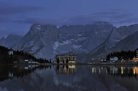 The mountain range Gruppo del Sorapis and hotels at night along lake Lago di Misurina in Auronzo di Cadore