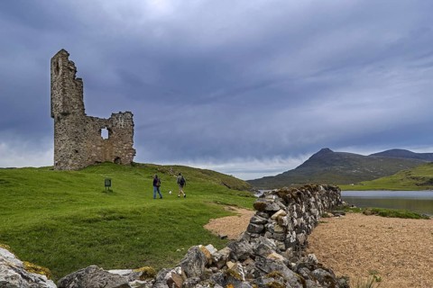 Tourists visiting 16th century Ardvreck Castle ruin at Loch Assynt in the Scottish Highlands