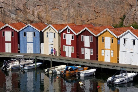 Colourful traditional fishing huts and boathouses along wooden pier at Smoegen