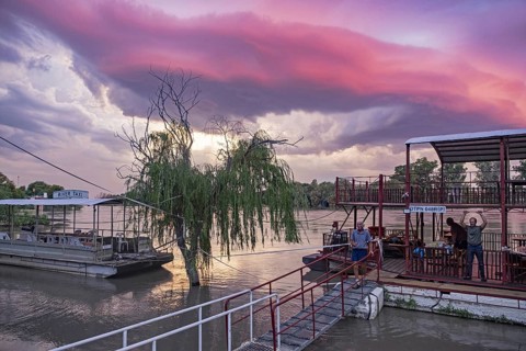 Western tourists and river taxis on the Orange river at sunset near Upington