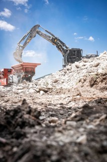 Black tracked excavator during demolition recycling on construction site