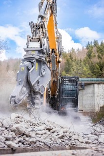 Yellow Liebherr crawler excavator with spreader recycling on demolition site