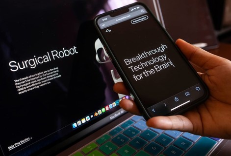 In this photo illustration a person browses Neuralink website on a smartphone