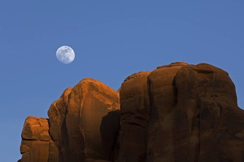 Red sandstone cliffs at sunset with full moon in the sky