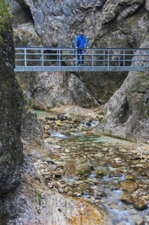 Tourist on footbridge over the river Almbach running through the Almbachklamm canyon in the Berchtesgaden Alps