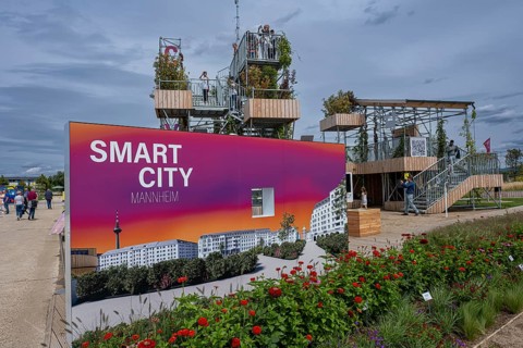 Sign saying Smart City Mannheim in front of viewing platforms on metal scaffolding overgrown with green plants at the Federal Horticultural Show