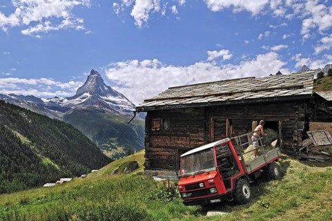 Farmer on Reform Muli vehicle storing hay in traditional wooden granary