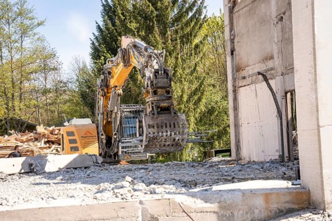Yellow Liebherr crawler excavator with grapple recycling on demolition site
