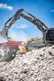Black tracked excavator during demolition recycling on construction site