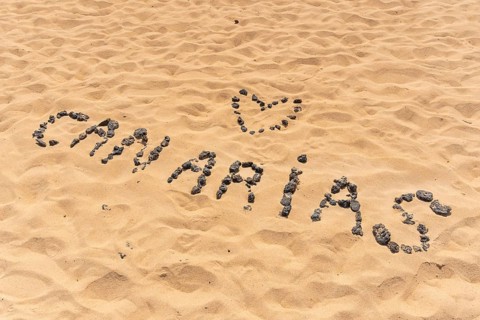 Canary name with black stones on the beach of the dunes of the Corralejo Natural Park