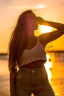 Summer lifestyle. A young blonde Caucasian woman in a white short wool sweater on a beach sunset