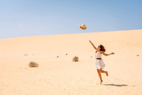 Tourist throwing his hats up very happy in the dunes of the Corralejo Natural Park