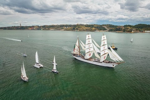 Aerial drone view of tall ships with sails sailing in Tagus river towards the Atlantic ocean in Lisbon
