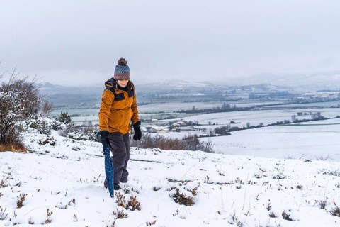 Young girl in yellow jacket playing in the snow with an umbrella. Snow in the town of Opakua near Vitoria in Araba