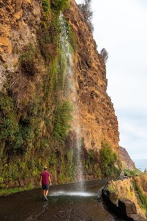 A young man looking at the waterfall that falls on the road called Anjos Waterfall