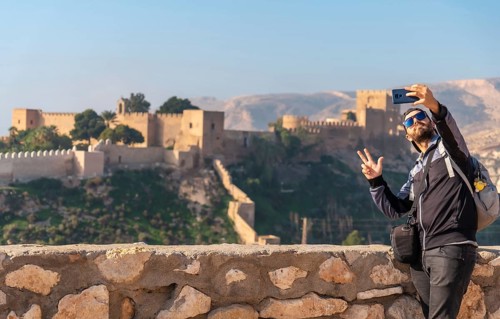 A young tourist taking a selfie at the viewpoint of Cerro San Cristobal de la Muralla de Jairan and the Alcazaba in the town of Almeria