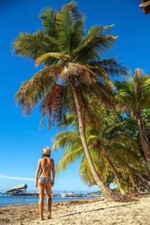 A young girl on top of a log dancing on West End beach on Roatan Island. Honduras