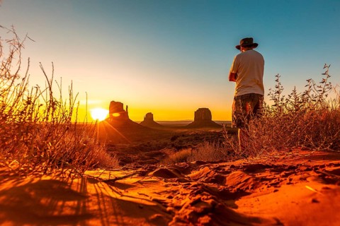 A lifestyle boy with a hat at dawn in Monument Valley