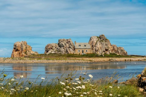 House between rocks next to a beautiful lake