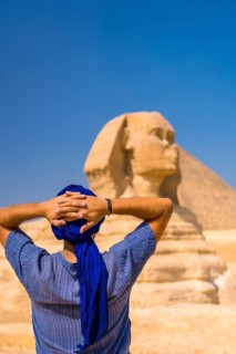 A young tourist enjoying and admiring the Great Sphinx of Giza dressed in blue and a blue turban. Cairo