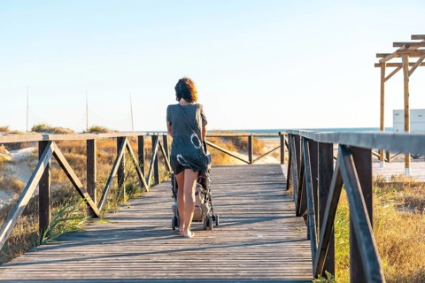 A young mother walking on the walkway of the Bateles beach in Conil de la Frontera