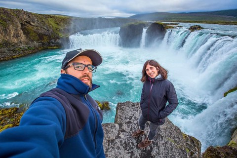 A young couple tourist looking at the Godafoss waterfall from above. Iceland