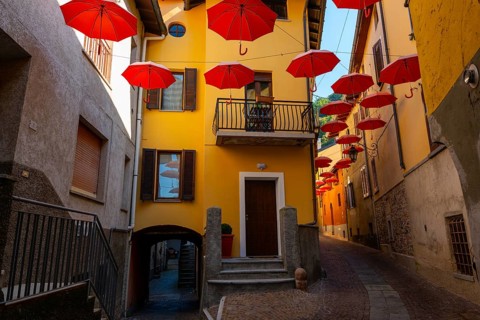 City Street in Porto Ceresio with Hanging Umbrellas in a Sunny Summer Day in Porto Ceresio