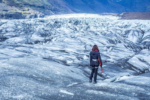 A young woman on her back with booties and hammer on the trekking of the Svinafellsjokull glacier. Iceland