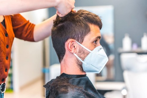 Hairdressers after the Coronavirus pandemic. Hairdresser with face mask and protective screen
