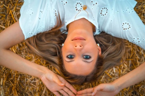A young blonde Caucasian woman in a white dress in a field of dry straw atop a haystack. In a dry cultivated field in Navarra