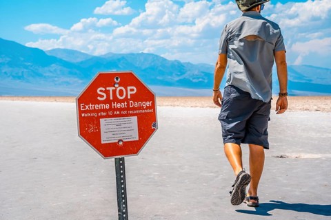 A man tourists walking white salt of Badwater Basin alerted by extreme heat