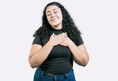 Positive latin girl with hands on chest. Grateful young woman with hands on chest. Grateful teenage girl smiling with hands on chest isolated