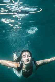 Image of a young woman diving with a white dress jumping into the sea