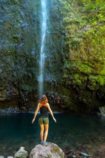 A young woman looking at the impressive waterfall at the Levada do Caldeirao Verde
