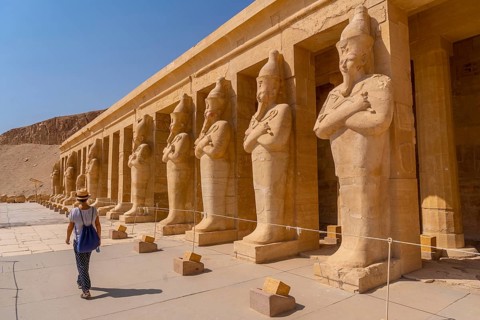 A young woman with pharaoh sculptures entering Hatshepsut's Funerary Temple in Luxor. Egypt