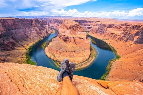 Crossed feet resting watching Horseshoe Bend and the Colorado River in the background