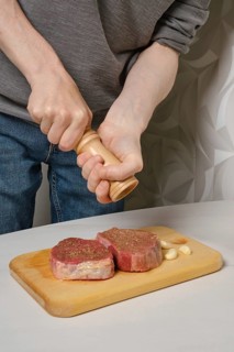 Sprinkling steak with salt from hand grinder