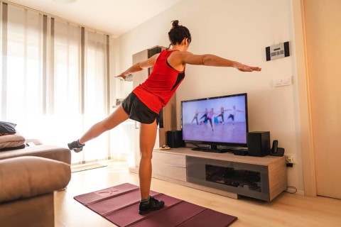 A young woman doing stretching in the room following the instructions of the online teacher. Sport in the covid19 quarantine at home